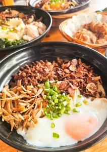 Raw egg Sabah chilli pan mee with crispy anchovies, minced pork, spring onions in traditional black bowl