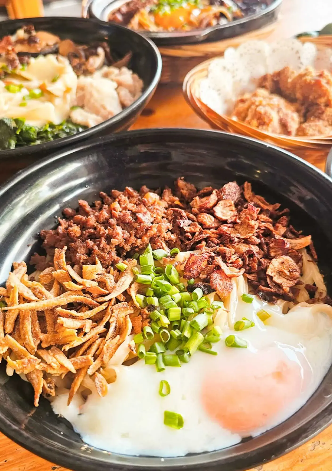 Raw egg Sabah chilli pan mee with crispy anchovies, minced pork, spring onions in traditional black bowl